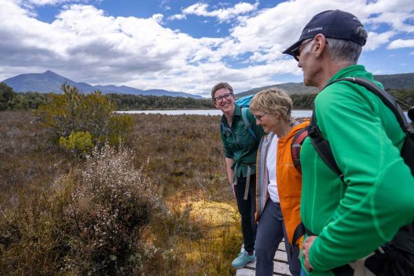 hikers on boardwalk with Trips & Tramps guide on the Kepler Track